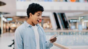 African Dominican guy surprised with phone number ringing looking at screen man answering unexpected call talking smiling laughing happy chatting cellphone friendly casual talk with good news offer photo