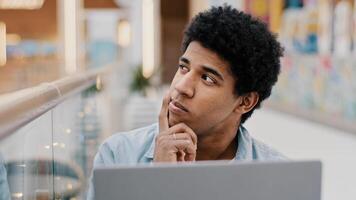 Pensive male african american guy rubbing chin thinking solution problem plan strategy startup idea sitting with laptop indoor male writer composing novel journalist working deep in thought difficulty photo