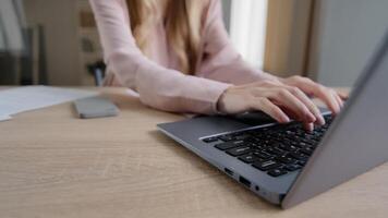 Close-up female hands with papers sorting documents typing on laptop at table in office. Unrecognizable caucasian business woman teacher paperwork at home bills payments contacts with computer busy photo
