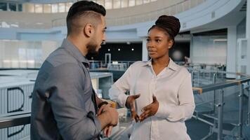 African American woman and Arabian Indian businessman talking in loft office hall working break diverse colleagues discussing news project in casual coworking atmosphere good relations at workplace photo