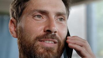 Smiling 40s happy adult professional cheerful businessman with toothy smile making business call talking phone in office agree say Caucasian bearded man salesman enjoying mobile conversation indoors photo