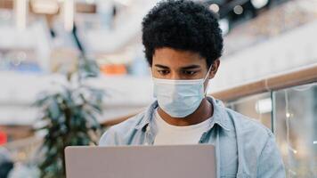 Portrait african american guy student user business man in medical mask thinking plan creates idea strategy working with laptop thoughtful pondering solving problem with computer application thinks photo