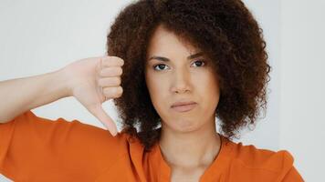 Close up African American millennial sad frustrated disappointed woman with curly hair girl looking camera showing dislike thumb down disagreement disgust rejection sign bad attitude gesture refusal photo