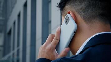 Back view from behind unrecognizable man in formal suit businessman leader salesman talking mobile phone outdoor in city remote distant virtual talk with smartphone cell conversation negotiate outside photo