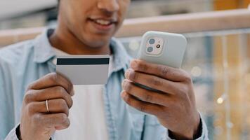African american thoughtful man client customer entering banking credit card data in phone mobile pays purchase choosing goods online decides internet payment financial transfers virtual money net app photo