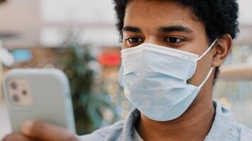 African american masked guy man in medical mask surprised message received wins online bets looking at mobile phone with wide open eyes surprise end pandemic news unexpected good result in smartphone photo