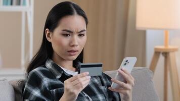 Angry puzzled Asian woman try to pay with e-bank app online service has problem with credit card blocked financial limit not activated for internet payment unsuccessful transaction with phone error photo