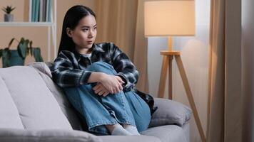 Alone offended sad thoughtful Asian woman upset frustrated girl looking away thinking of problems sitting at home worries troubled negative bad mood broken heart quarrel with boyfriend pms syndrome photo