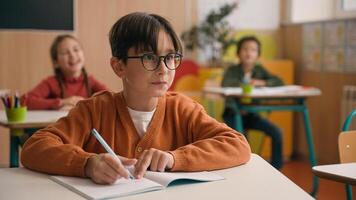 Caucasian little boy kid schoolboy nerd in glasses write task class lesson school education angry children cruel throw crumpled paper balls abuse abusing bullying classmates studying problem mock photo