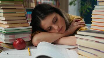 Sleeping napping woman girl tired exhausted female high school student sleep on table desk pile books overwork prepare exam boring education study in university college academy library fall asleep nap photo