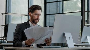 Upset tired exhausted burnout adult worker manager businessman sitting in office with paperwork difficult task incorrect data in papers and computer error throws documents holding head with sad photo