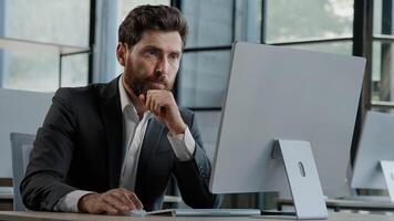 Busy pensive focused Caucasian bearded adult 40s man CEO company worker manager boss businessman working on computer in office searching solution of problem decide difficult creating online thinking photo