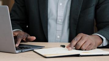 Close-up male hands writing in notebook with pen make notes information financial analysis startup project management idea sitting at desk in office using laptop unrecognizable middle-aged businessman photo