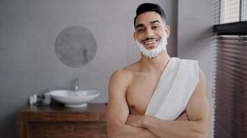 Handsome confident naked Arabian man 30s muscular male guy standing in bathroom at home in hotel shower looking at camera with white foam shaving gel on beard face crossing arms posing ready for shave photo