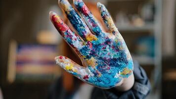 Caucasian red haired woman artist designer painter girl show dirty in paints colorful palm at camera holding hand in front of her close face with arm stop gesture not no in art studio after painting photo