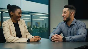 Arabian Indian businessman and African American businesswoman talking at office discuss project business idea sitting at table. Diverse partners colleagues woman manager and man executive negotiating photo