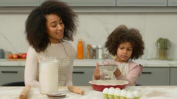 African American mom help little kid daughter cooking together make dough in kitchen happy family prepare cake ingredients pie baking pastry child girl sieve sifts mother pour flour teamwork photo