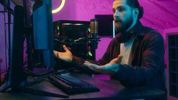 Caucasian gamer man addict puzzled influencer streaming play videogame blog computer screen surprise confused male guy blogger removing headphones shock scam losing game cheat e-sport problem at home photo