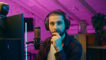 Puzzled thoughtful Caucasian influencer guy blogger player streamer man vlog contemplating cyber sport neon thinking gaming decision at home addict male gamer host play computer game blog idea thought photo