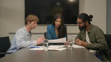 Three multiracial businessmen businesswoman team reviewing sales data documents paperwork teamwork discussion diverse business men woman colleagues coworkers company brainstorm talk at table at office photo