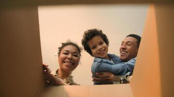 POV point of view open cardboard box looking inside African American happy family joyful parents son kid little boy child unpacking parcel delivery online shop receive package unboxing moving day home photo