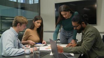 Multiracial businessmen businesswomen colleagues sit at conference table creative managers analyzing learn data charts graphs team meeting together group brainstorming discussion business paperwork photo