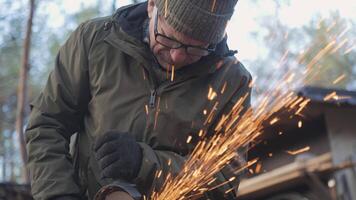 A craftsman is focused on shaping metal in an outdoor workshop. Bright sparks fly from the material as tools are skillfully used, surrounded by nature in a serene setting. video