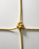 Artfully arranged yellow rope knot showcasing intricate design and texture on a clean background photo