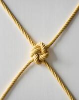 Artfully arranged yellow rope knot showcasing intricate design and texture on a clean background photo