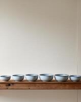 Six bowls sit on a shelf in a room photo