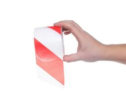 Man holds in his hand a protective signal tape with red stripes on a white background, isolate. Close-up, damage photo