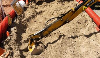 A yellow boom with a bucket near a children's mini excavator in an amusement park. Entertainment for children. photo