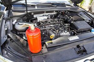 Car fire extinguisher on the background of the car engine. Extinguishing class of fire extinguisher, expiration date. Copy space for text photo