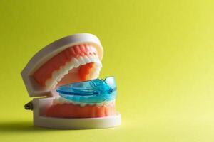 Dental mouth guard for bruxism with a mock-up of a dental jaw on a yellow background. Concept for treatment and protection of teeth from grinding during sleep in children. Copy space for text photo