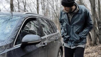 Homeless man walks up to someone else's car, male burglar robber looks through the slightly open window of auto's door and walks away. Vehicle with alarm system. Property insurance against theft crime photo