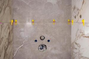 Laying modern large format tiles with the tile leveling system in the toilet. Laying tiles on the wall of the installation for the toilet. Copy space for text photo