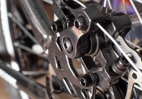 Brake system of a caliper and a metal brake disc on a bicycle, background, macro photo