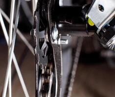 Gearshift on mountain bike MTB, chain moves on rings. Changes speeds. Shift gears on bicycle crank. Work of chain drive chainset. Front derailleur. Macro closeup low angle shot. Wheel spins and turns photo