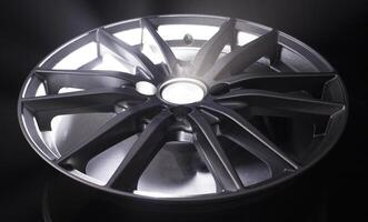 Modern beautiful car alloy wheel in the form of rays that is highlighted by rays of light and sparkle, black background photo
