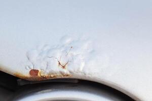 Corrosion and rust on the hood of a car. The concept of anti-corrosion treatment of the car body, macro photo
