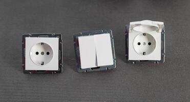 Set of modern electrical devices for the home. Electrical socket with a protective cover, a two-gang switch on a gray background. Close-up photo