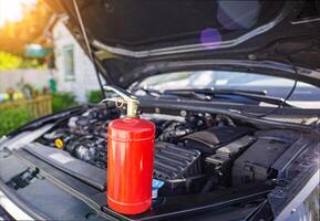 A car powder fire extinguisher is in a car with an open hood. The concept of modern fire extinguishers for extinguishing a fire in a car. Copy space for text photo