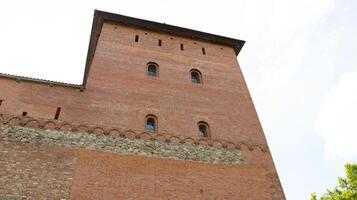 An ancient large castle tower with small red brick windows. Historic building of the 14th century photo