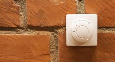 Modern white room and floor heating controller on a brick wall, close-up. Adjustment of the comfortable temperature in the room. Copy space for text photo