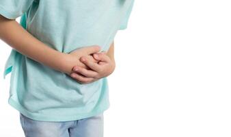 A child holds his stomach with his hands on a white background, close-up. Abdominal pain in children due to helminths, weight loss and poor health. Copy space for text, isolate photo