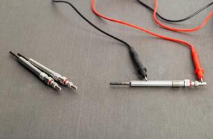 Checking the serviceability of the glow plug with a multimeter. Glow plug voltage resistance. Modern heating element, close-up photo
