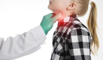 The hand of an endocrinologist palpates the thyroid gland of a seven-year-old girl. Concept of dysfunction of thyroid hormones. Lack of iodine, hypothyroidism. Copy space for text photo