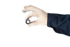 An auto mechanic holds in his hand a faulty timing belt idler on a white background, isolate. Close-up, inspection photo