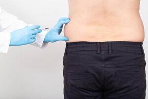 A specialist doctor makes slimming injections into the lateral fat layer. Fat burning on the sides, liposuction photo