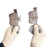 An auto mechanic holds in his hands old worn out brake pads on a white background, isolate. The concept of replacing brake pads with new ones photo